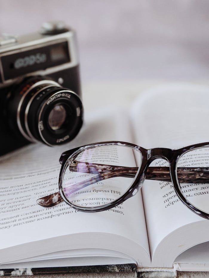 Mastering the First Impression: Your intriguing post title goes here A close-up of a vintage camera, stylish eyeglasses, and an open book, capturing a nostalgic mood.