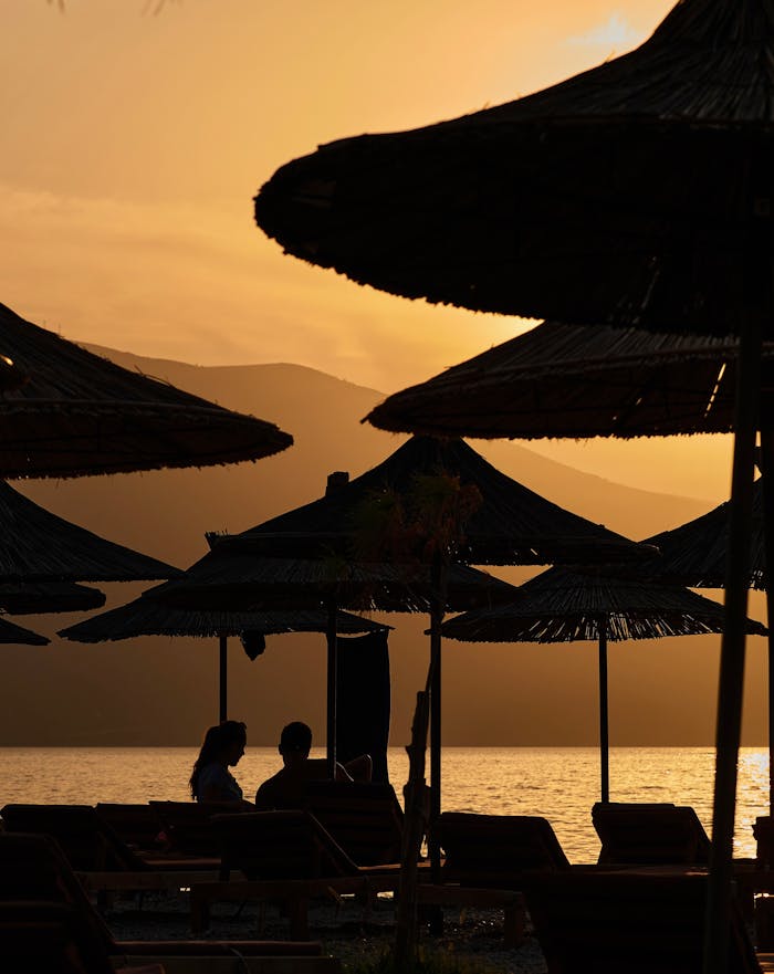 Couple enjoying a sunset at Vlorë Beach, Albania, under beach umbrellas. Perfect vacation moment.