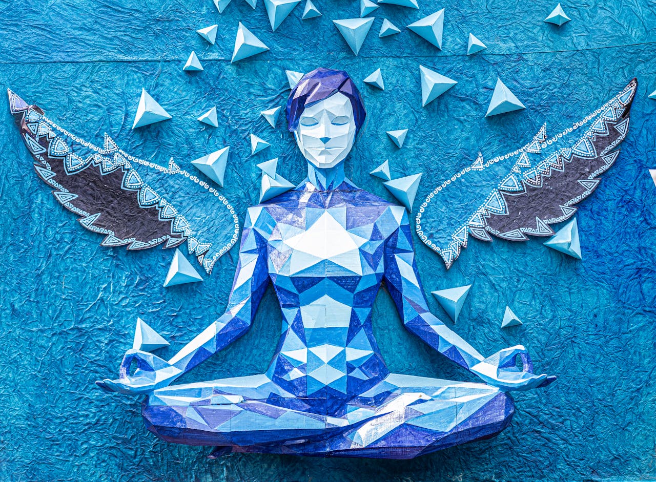 Vibrant blue origami angel sculpture in yoga pose with decorative wings and geometric design
